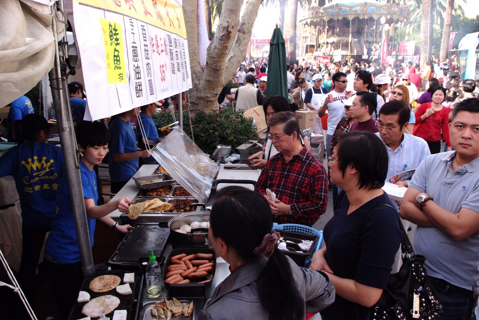 Outdoor food vendor stall with a crowd of visitors